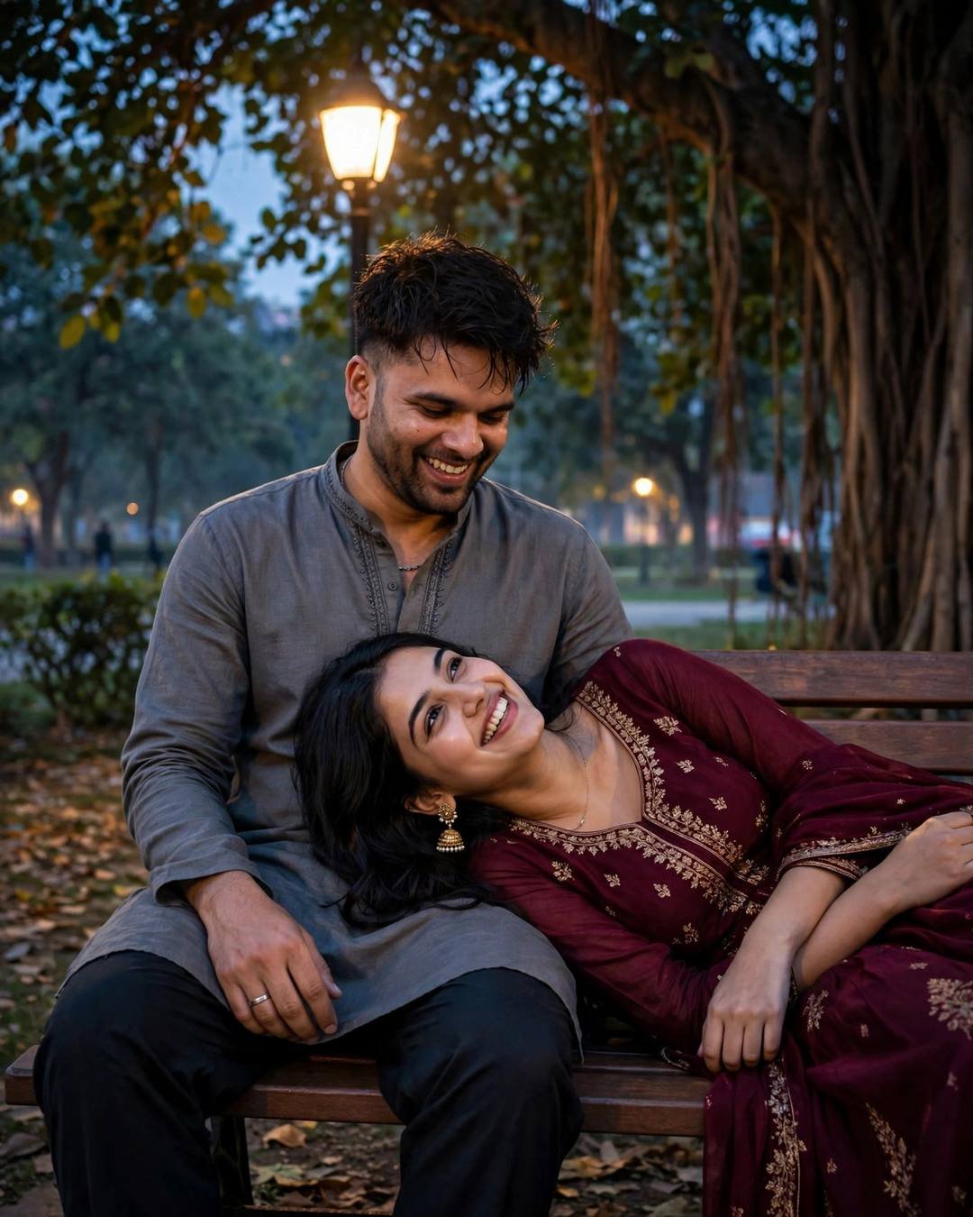 Young Indian couple on a park bench at night under a lone lamp, her head resting in his lap, both laughing